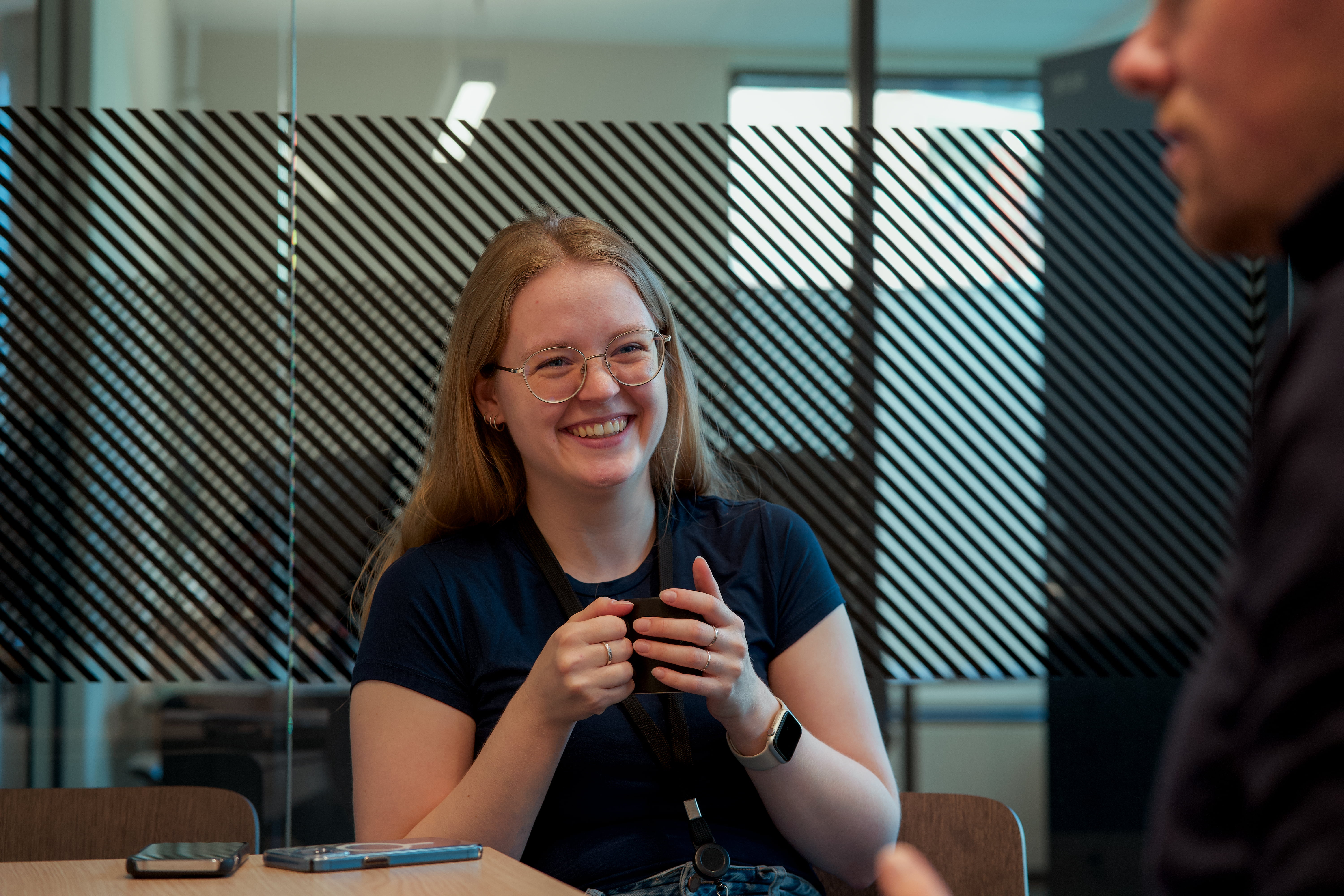 Smilende førstegangskjøper som sitter med en kaffekopp i hånden i et rådgivermøte