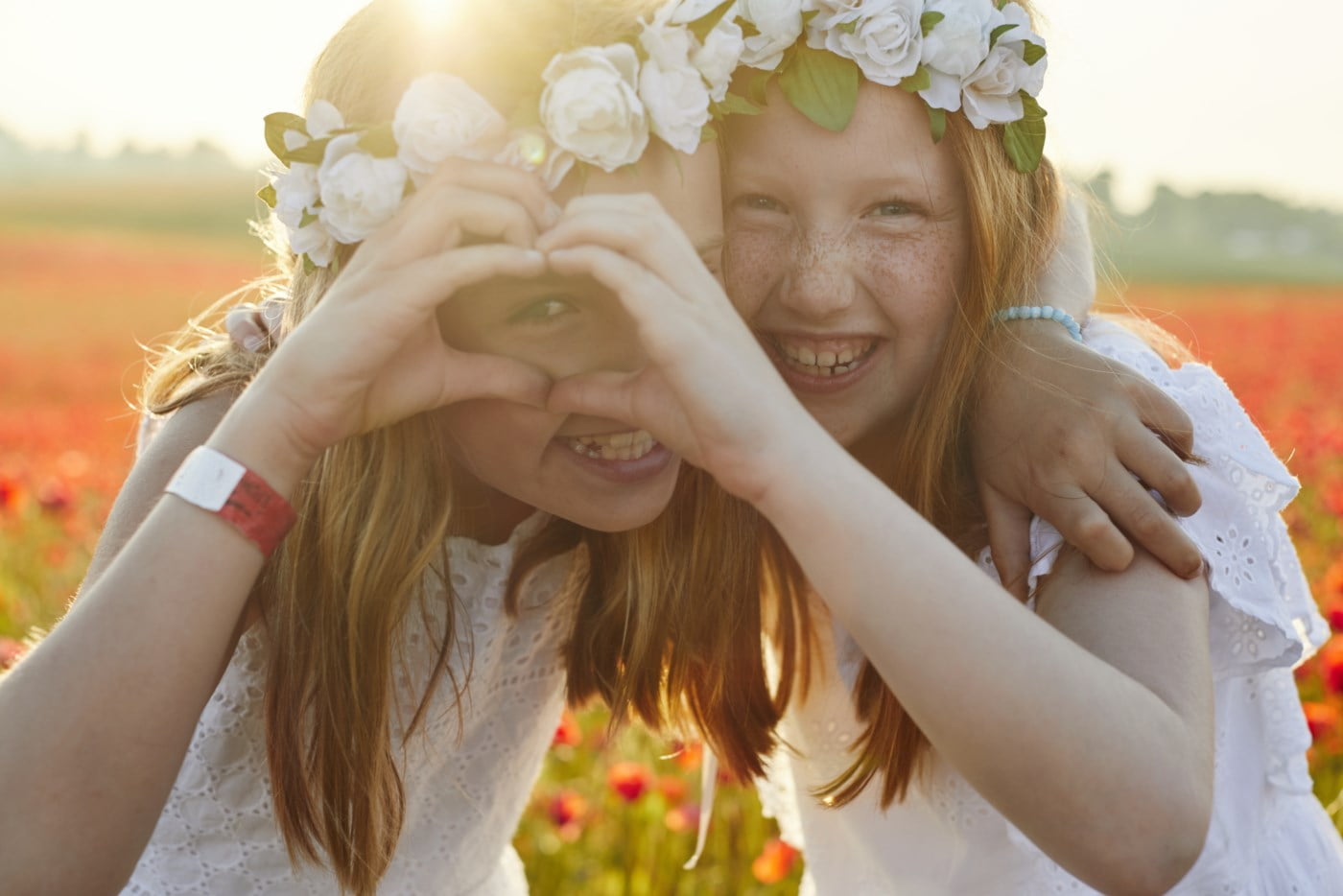 to smilende jenter med blomsterkranser i håret